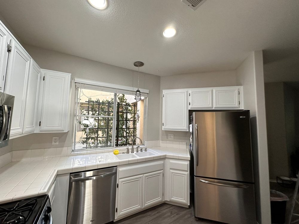 White kitchen cabinets around a window and tile counters